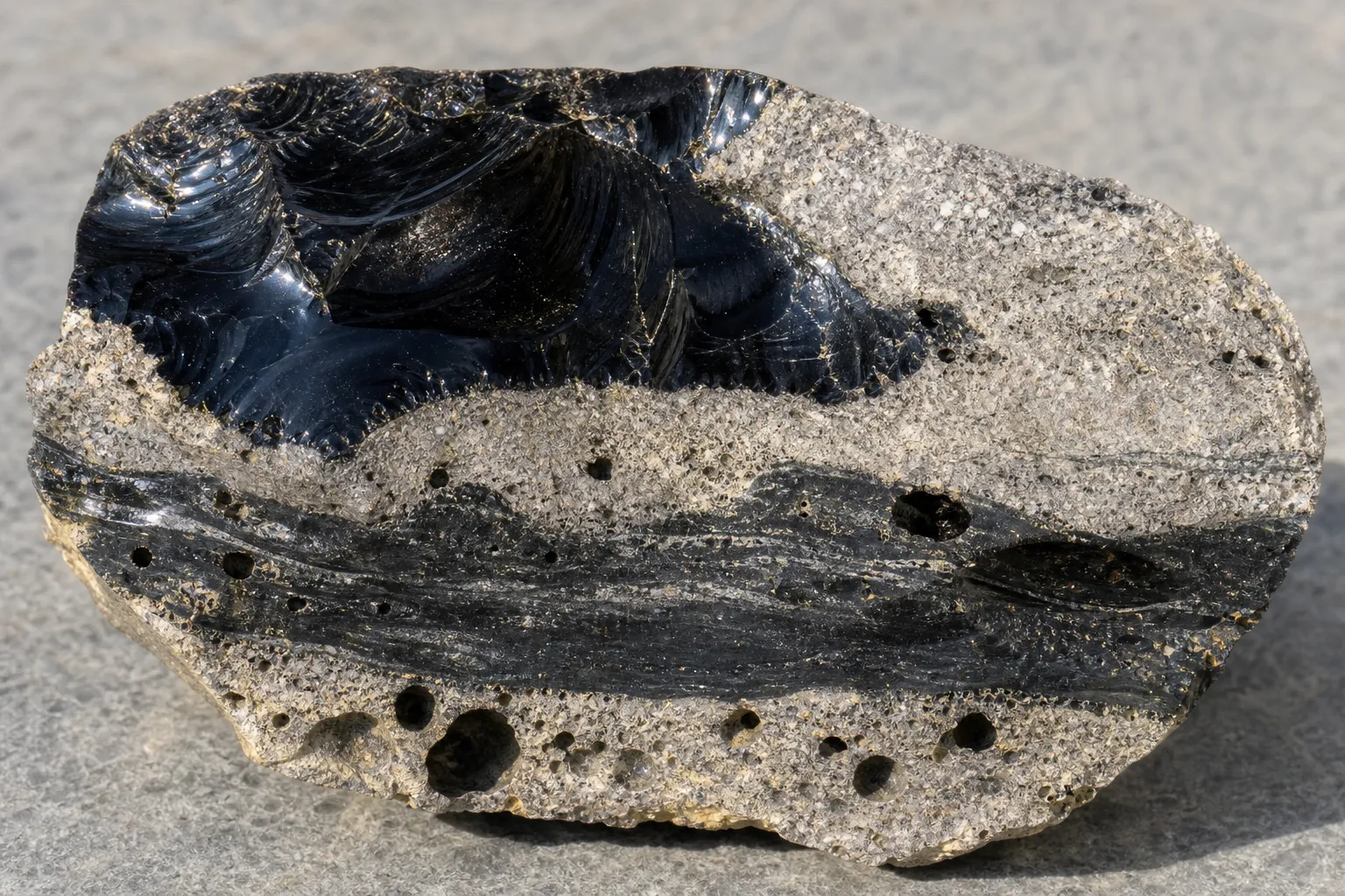 Obsidian-bearing volcanic material with glassy zones and contrasting textures from different cooling histories