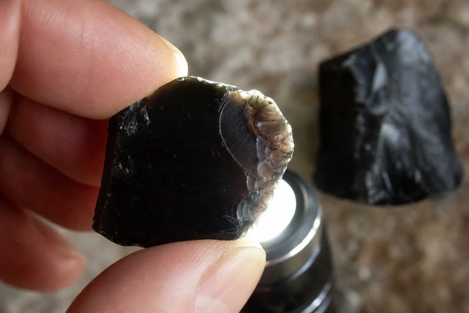 Thin edge inspection of a dark glassy stone showing why translucency is useful but not proof