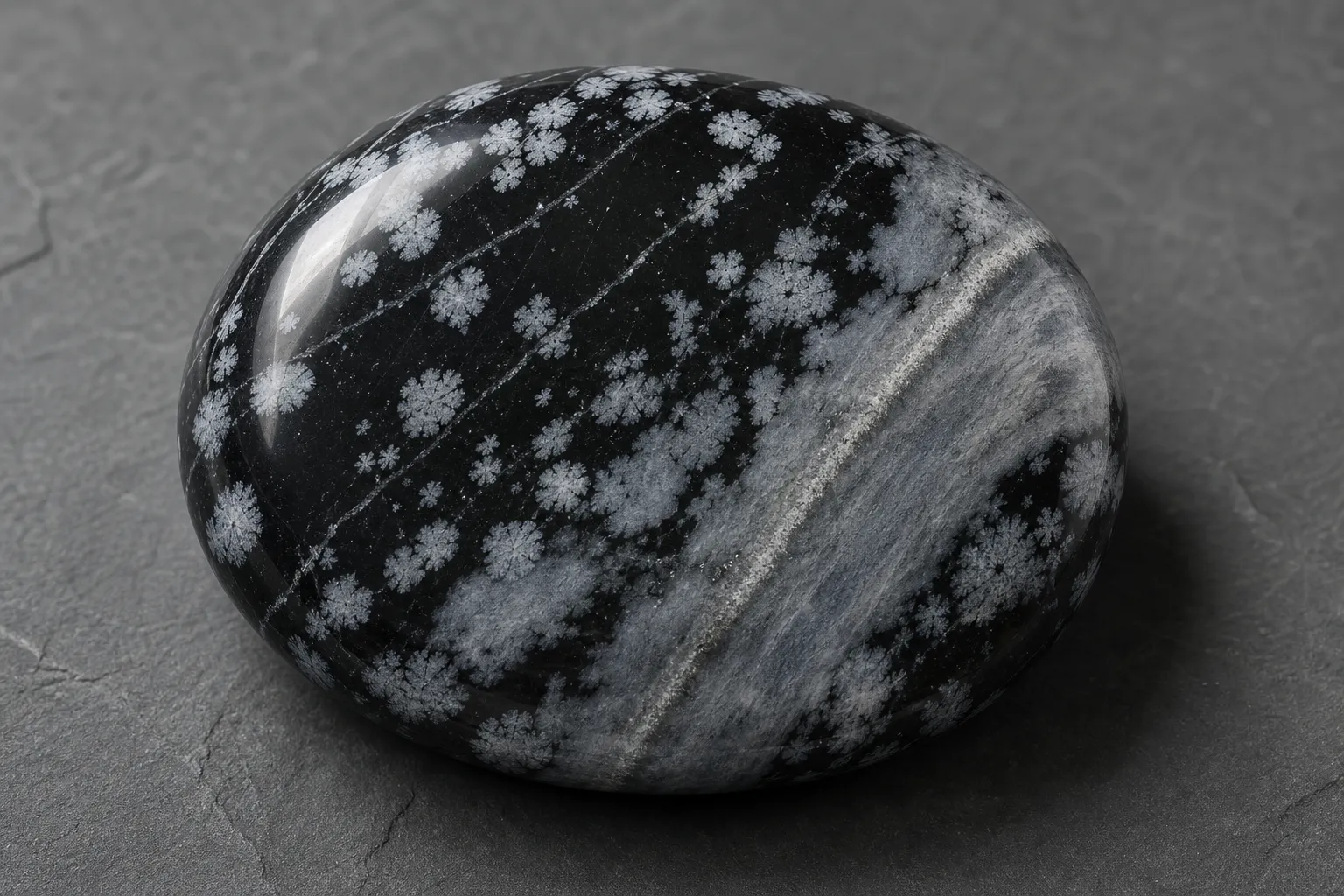 Polished snowflake obsidian showing pale lines, bands, and cloudy gray-white patches on a dark glassy surface