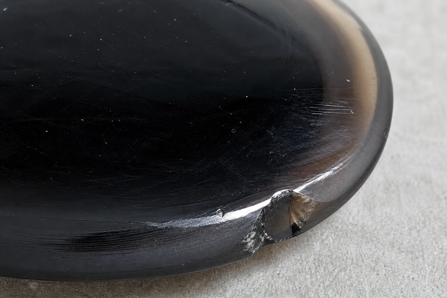 Black obsidian with a thin edge showing smoky gray and brown tint under bright light