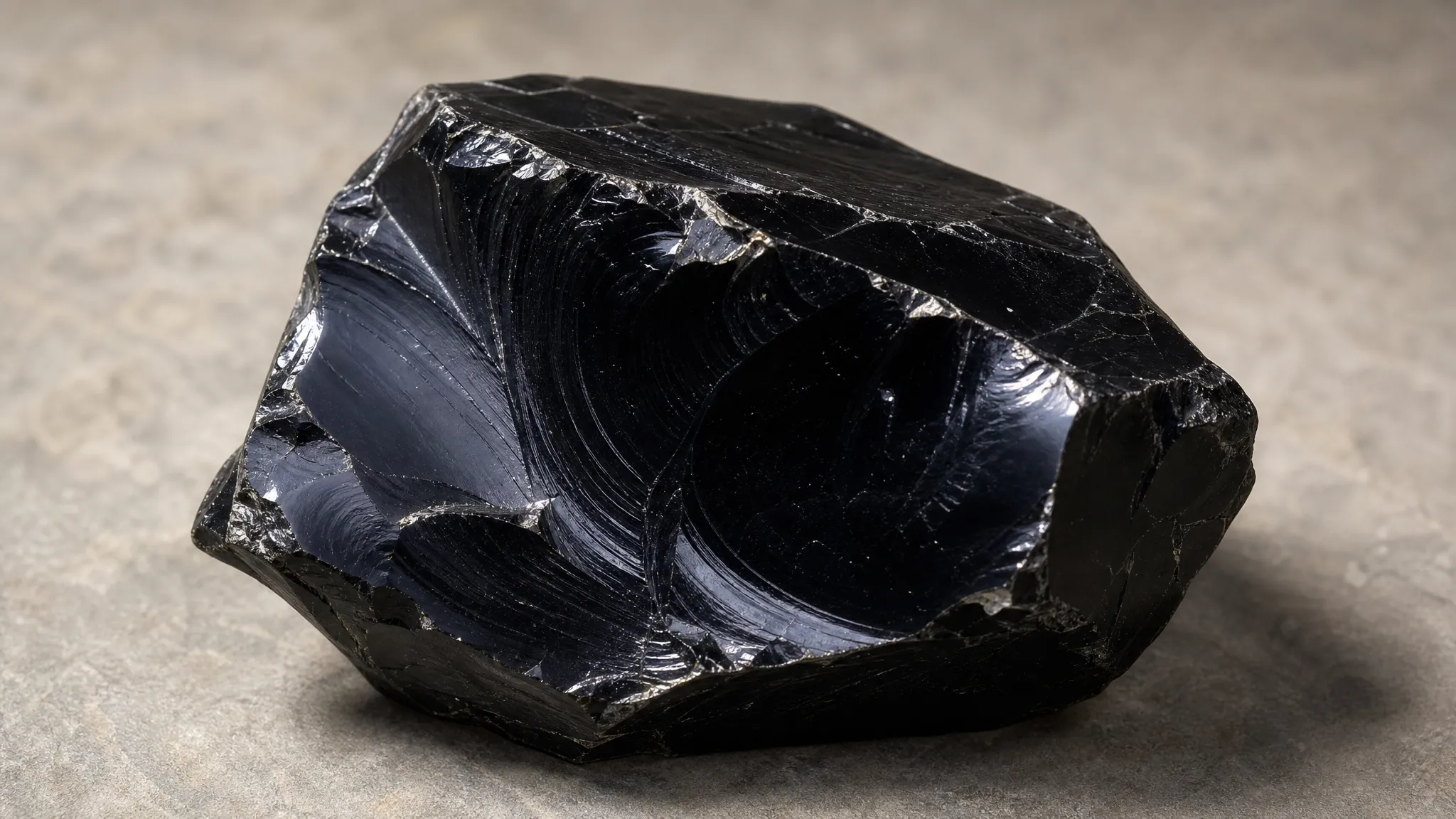 Broken obsidian showing glossy curved fracture faces and sharp glass-like edges